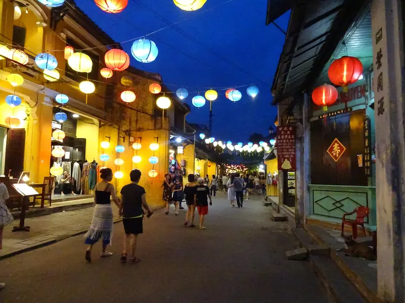 Silk lanterns strung above a yellow-walled street in Hội An at dusk